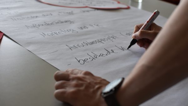 Teilnehmer schreibt auf Plakat