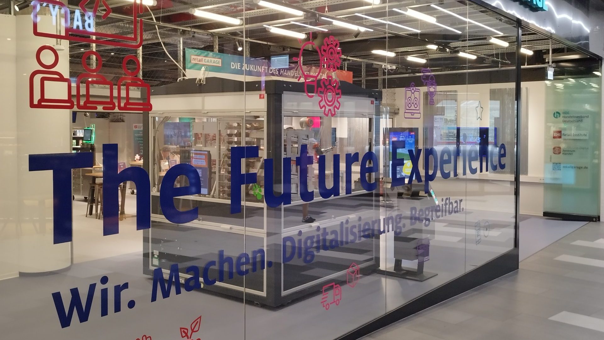 Schaufensterscheibe mit der Aufschrift "The Future Experience - Wir. Machen. Digitalisierung. Begreifbar."