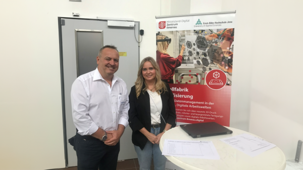 Am Stand der Modellfabrik Ein Mann und eine Frau stehen vor einem Banner der Modellfabrik Virtualisierung.