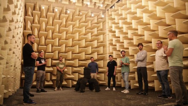 3D-Präsentationsraum Eine Gruppe von Menschen steht in einem Raum, welcher mit Lautsprechern ausgedeckt ist.