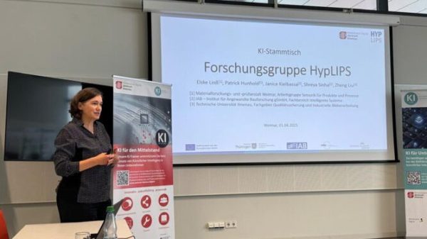 Vorstellung der Forschungsgruppe Eine Frau steht vor einer Präsentation und einem Roll-Up