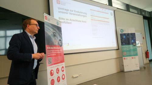 Ein Mann steht vor einer Präsentation und einem Roll-up
