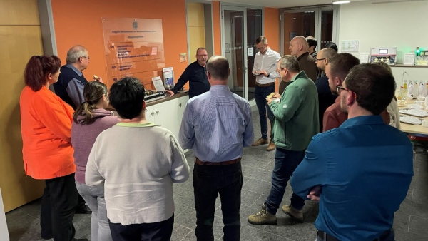 Jahresauftaktveranstaltung der Deutschen Gesellschaft für Qualität eine Gruppe von Menschen vor einem Wegweiserschild der Verantaltungslocation