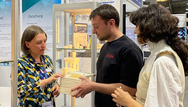 Dr. Kerstin Michalke (links) am Messestand Drei Personen am Messestand auf der RapidTech