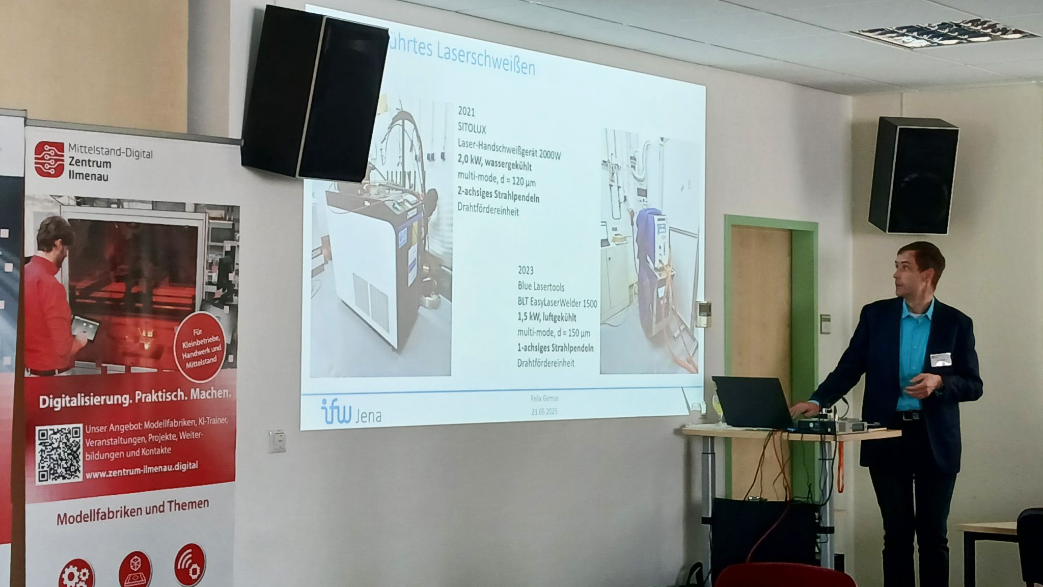 Vortrag zum Thema Laserschweißen Referent steht vor einem Beamerbild