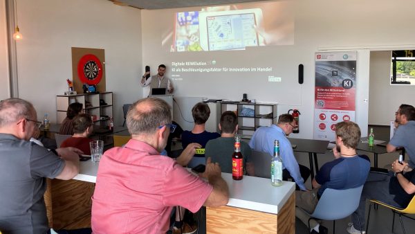 Teilnehmer des Juni-KI-Stammtischs Personen an Tischen schauen auf einen Referenten