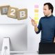 Mann steht vor Laptop und zeigt auf die Buchstaben "B2B"