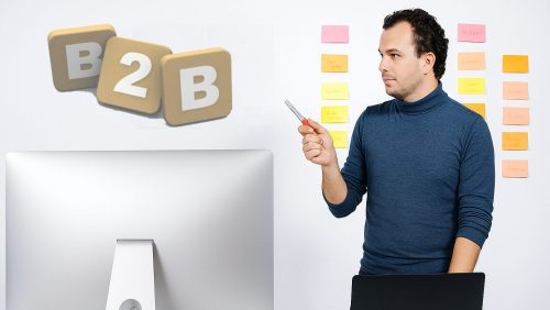 Mann steht vor Laptop und zeigt auf die Buchstaben "B2B"