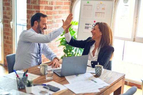 Mann und Frau im Businesskontext geben sich ein High-Five