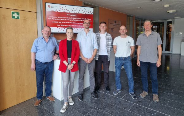 Führung durch die Modellfabrik Smarte Sensorsysteme Eine Gruppe Menschen vor einem Bildschirm der sie im Mittelstand-Digital Zentrum Ilmenau willkommen heißt