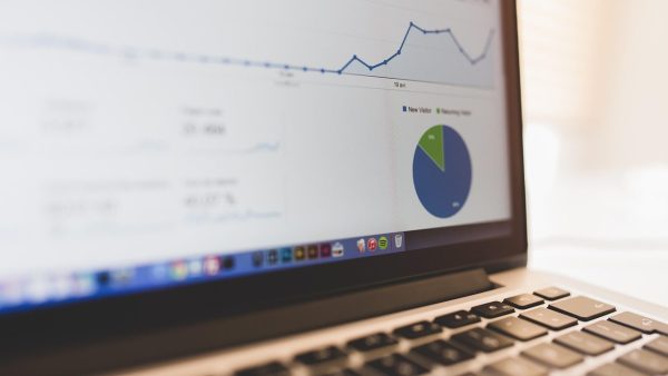 Datenanalyse Nahaufnahme eines Laptop-Bildschirms mit Datenanalyse-Dashboard, das ein Liniendiagramm und ein Kreisdiagramm mit den Kategorien ‚New Visitor‘ und ‚Returning Visitor‘ zeigt.