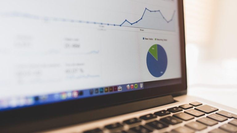 Nahaufnahme eines Laptop-Bildschirms mit Datenanalyse-Dashboard, das ein Liniendiagramm und ein Kreisdiagramm mit den Kategorien ‚New Visitor‘ und ‚Returning Visitor‘ zeigt.