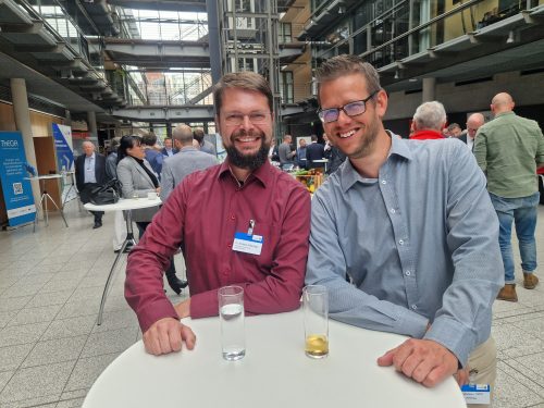 Zwei Personen stehen vor vielen Menschen