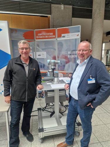 Zwei Personen stehen vor einem Roboter