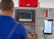 Arbeiter steht vor einer Maschine. An dieser ist ein Tablet befestigt