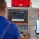 Arbeiter steht vor einer Maschine. An dieser ist ein Tablet befestigt