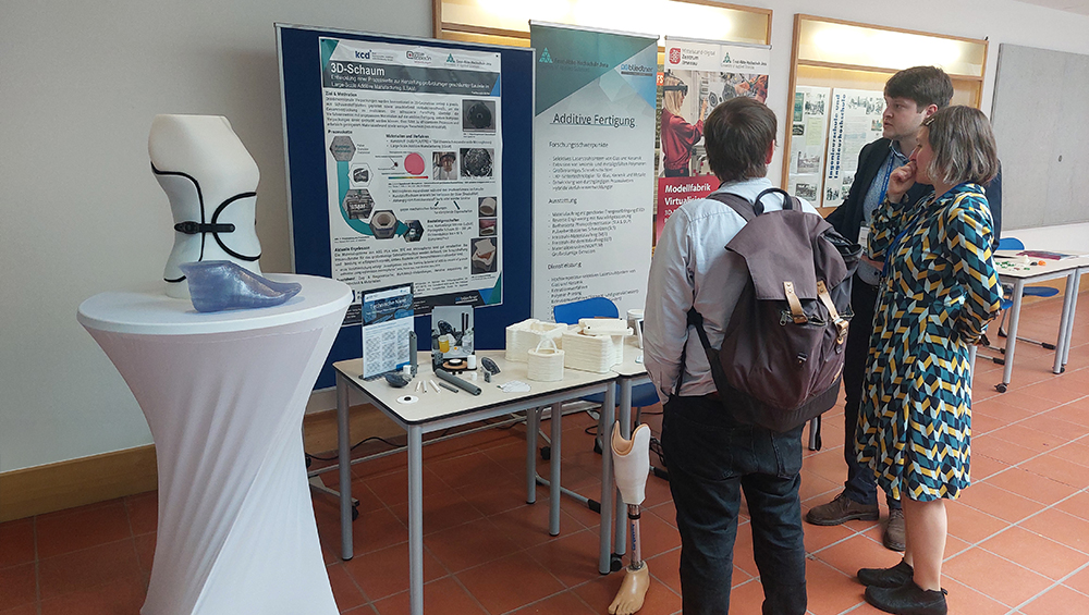 Menschen vor einem Messestand mit 3D-Druck-Exponaten