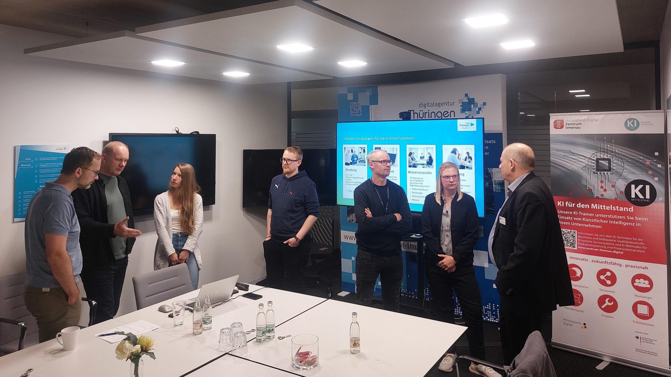 Personen stehen um einen Tisch und sprechen