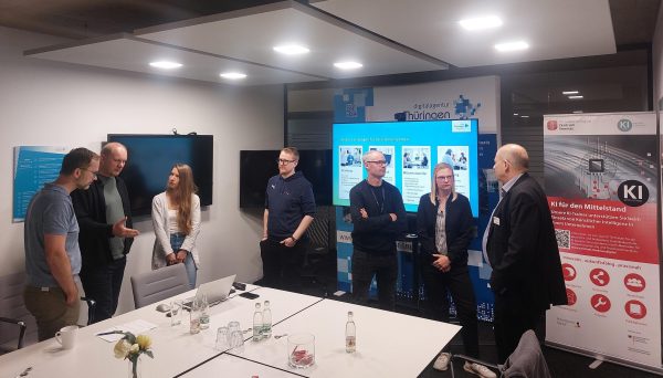 Personen stehen um einen Tisch und sprechen