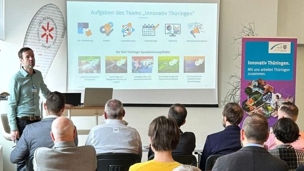 InnoMeet Menschen sitzen vor einem Referenten, der via Beamer etwas erklärt