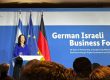 Katharina Reiche steht an einem Rednerpult und hält eine Ansprache vor Publikum. Hinter ihr sind die Flaggen Deutschlands, der Europäischen Union und Israels zu sehen. Auf einer großen blauen Wand im Hintergrund steht „German Israeli Business Forum“ mit einem Untertitel zur Partnerschaft und digitalen Innovation. Auf einem Bildschirm links neben der Rednerin wird ihr Name und ihre Funktion als Bundesministerin für Wirtschaft und Energie angezeigt. Im Vordergrund sind die Köpfe der Zuhörenden zu sehen.