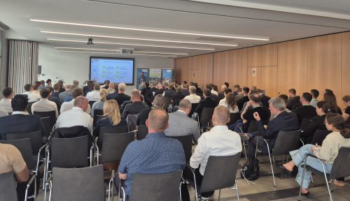 Zahlreiche Teilnehmende verfolgen einen Vortrag in einem voll besetzten Konferenzraum. Auf einer Leinwand werden Inhalte zu Innovation und Digitalisierung präsentiert.