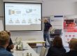 Referent erklärt vor Teilnehmenden die Crimphöhe und zeigt dazu eine technische Präsentation auf einer Leinwand.