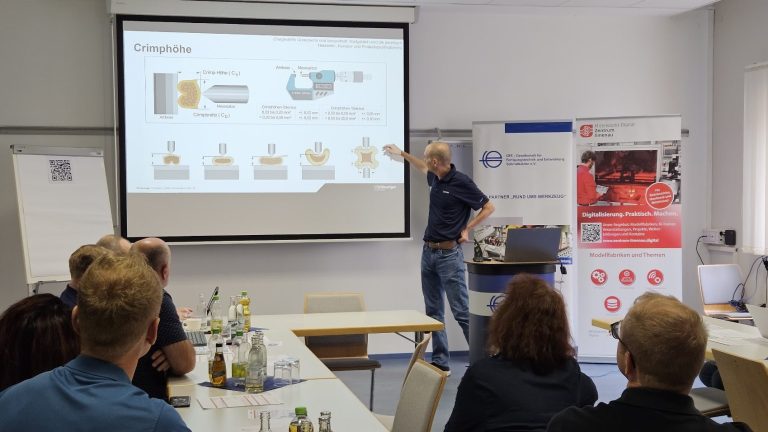 Referent erklärt vor Teilnehmenden die Crimphöhe und zeigt dazu eine technische Präsentation auf einer Leinwand.
