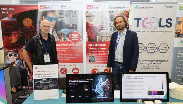 KI-basierte Visualisierung und digitale Fertigung Zwei Aussteller stehen vor Informationsständen zu KI-basierter Visualisierung, Prozessdaten und digitaler Fertigung mit mehreren Monitoren und Demonstrationsmaterialien.