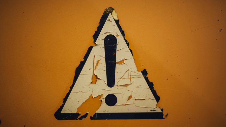 Warnung Warnschild an gelber Wand