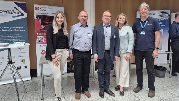 Fünf Personen stehen gemeinsam vor dem Informationsstand des Mittelstand-Digital Zentrums Ilmenau und weiteren Ausstellungsständen einer Fachveranstaltung.